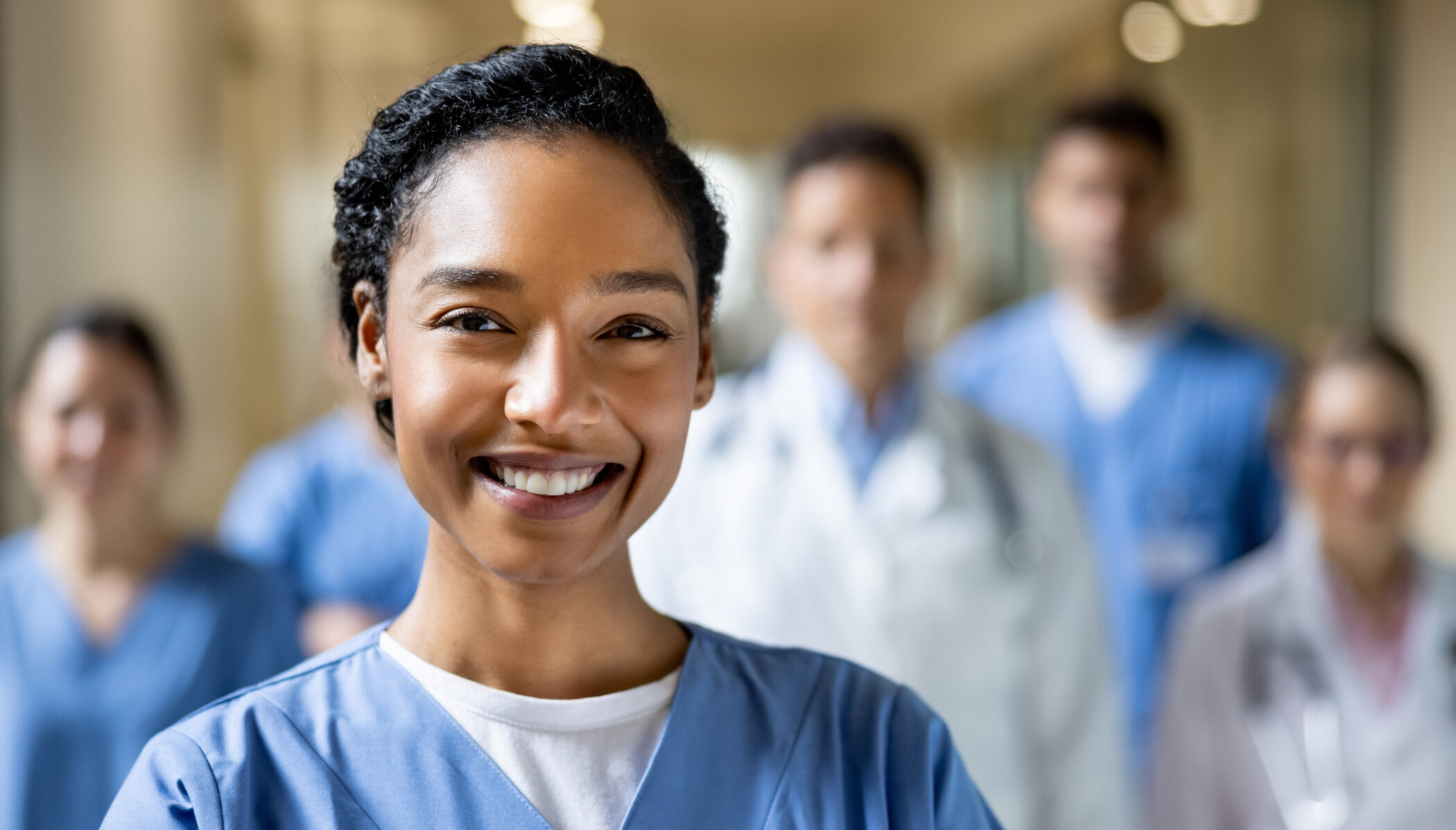 Happy chief nurse working at the hospital with a group of healthcare workers and looking at the camera smiling - medical staff concepts
