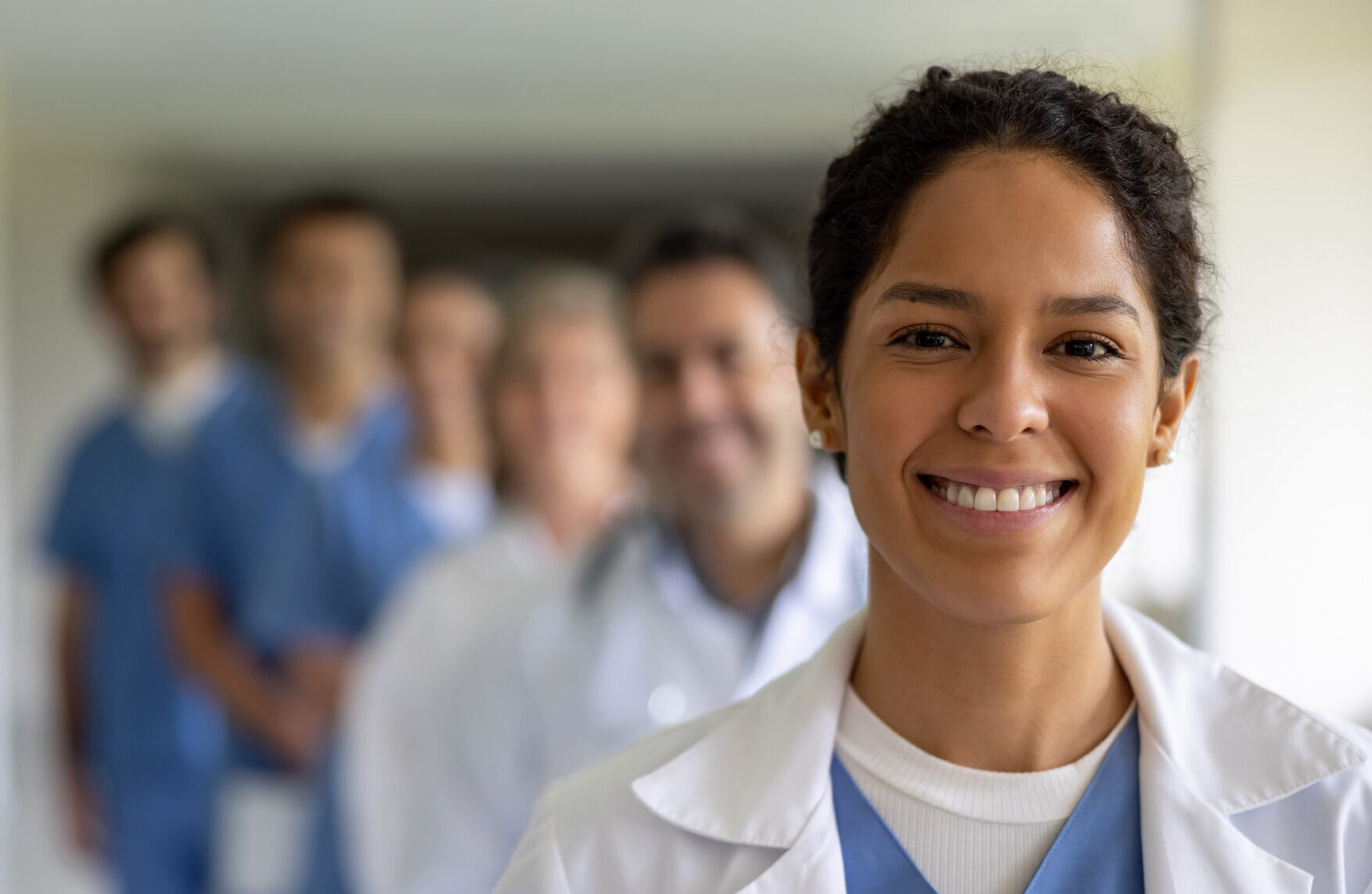 Happy Latin American female doctor leading a group of healthcare workers at the hospital and looking at the camera smiling