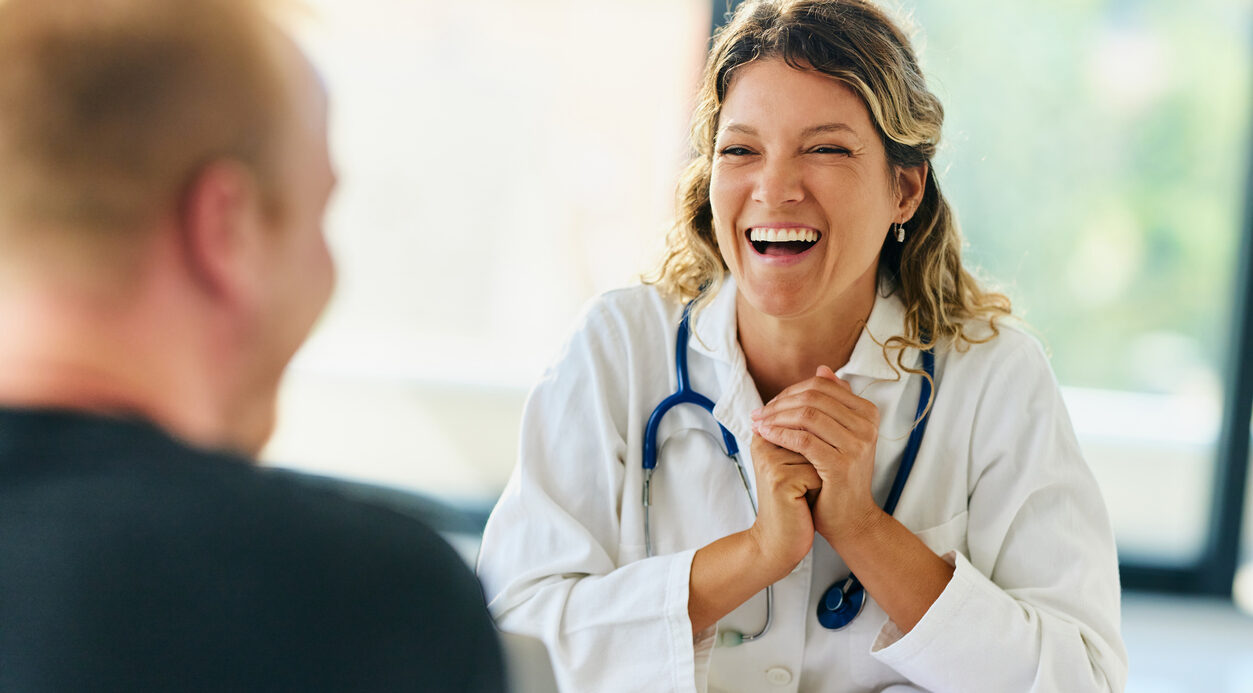 Happy female medical expert communicating with her patient during an appointment at doctor's office.