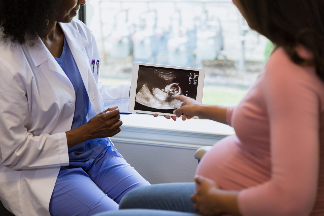 Doctor showing pregnant woman ultrasound on tablet
