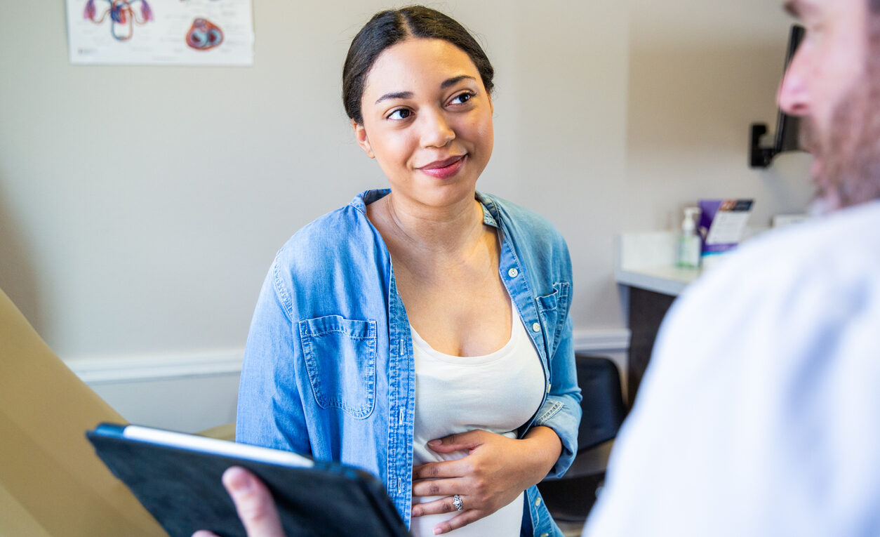 Young pregnant black woman receiving prenatal care at a medical office with a doctor