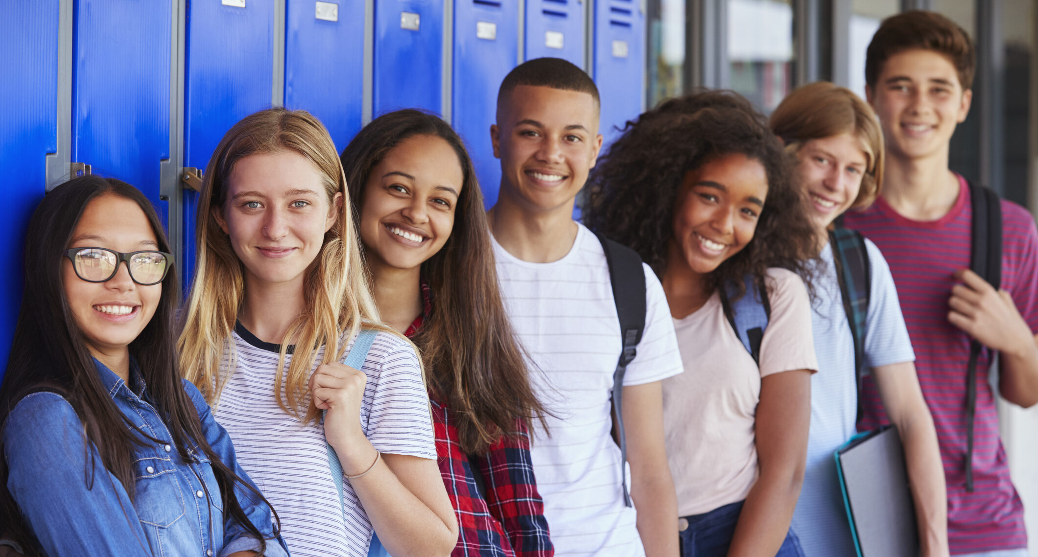 Teenage school kids smiling to camera in school corridor