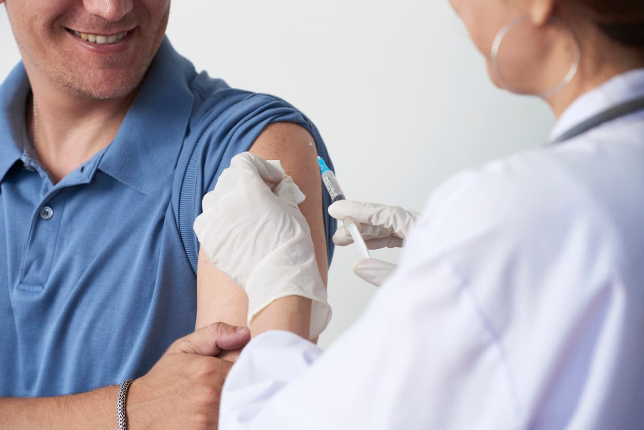 Man receiving a vaccine injection from a healthcare professional during a routine immunization appointment.