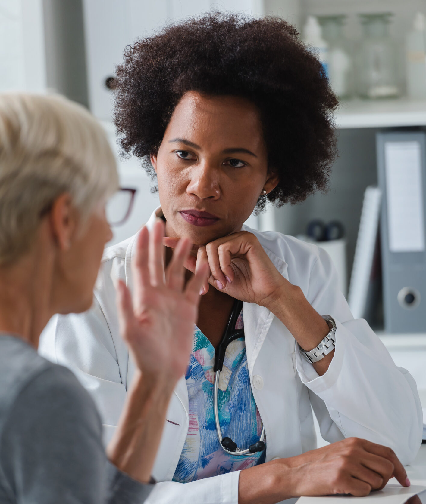 A female doctor sits at her office and examining elderly female patient