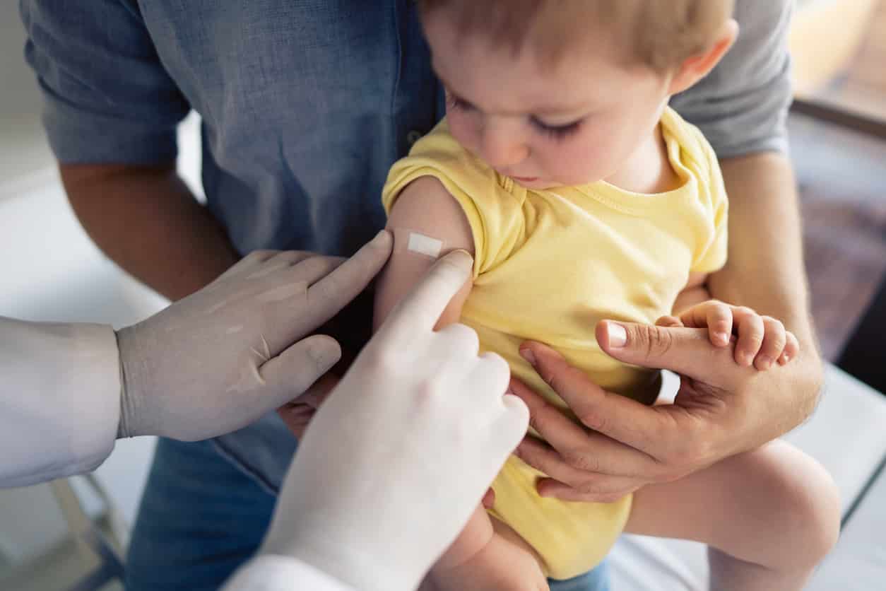 Toddler receiving a vaccine from a healthcare professional during a pediatric immunization appointment.