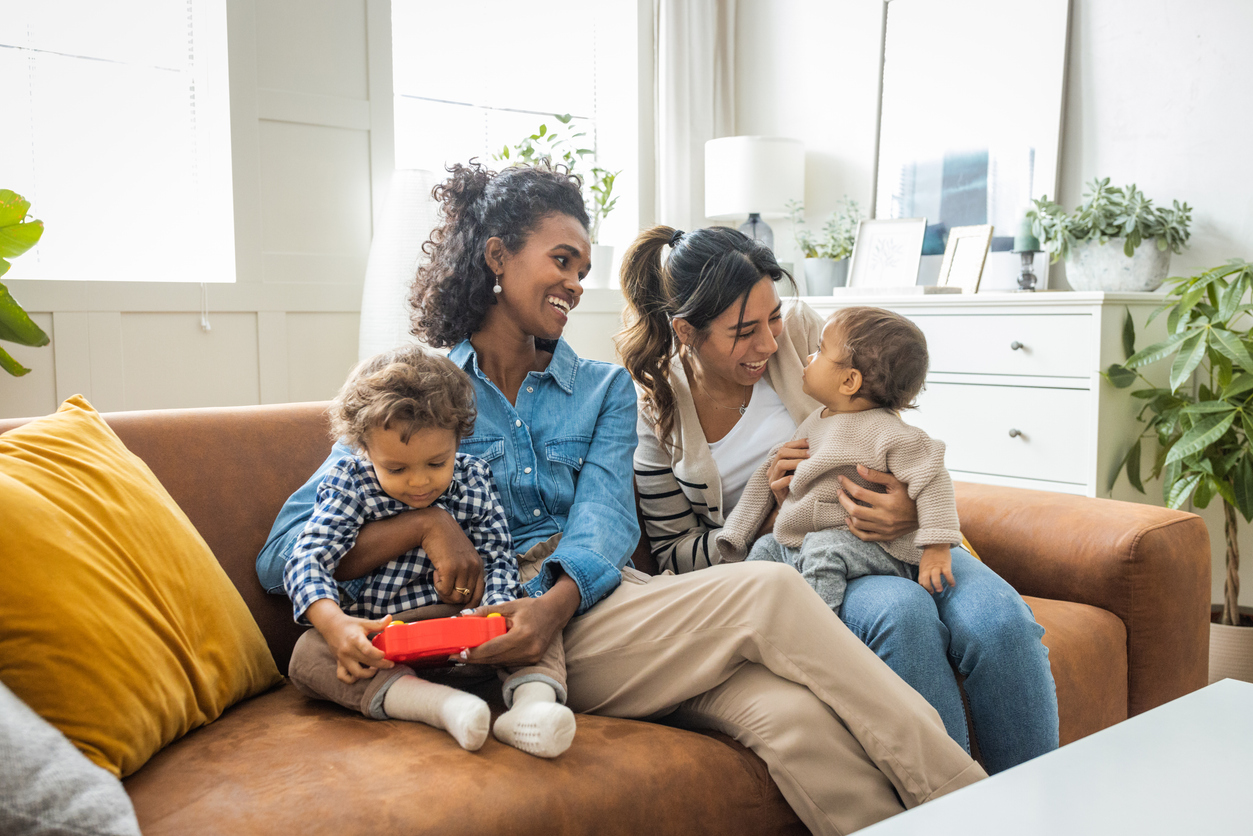 Young mothers playing with kids in living room.