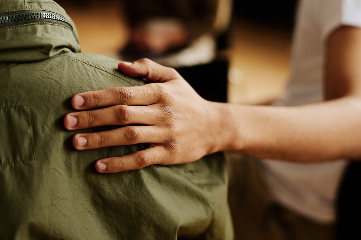 Supportive hand on a patient’s shoulder during a mental health counseling or emotional support session