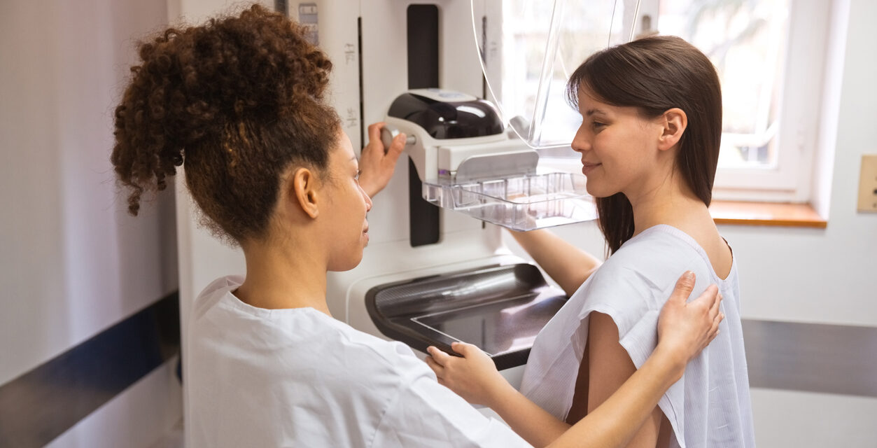 Female doctor talking to young woman during Mammography test