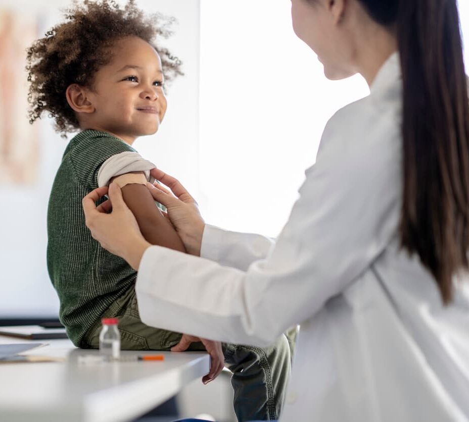 Smiling child receiving a vaccination from a pediatric healthcare provider during a routine wellness visit.