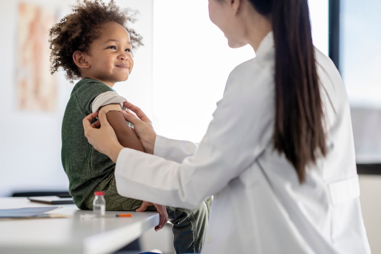 Smiling child receiving a vaccination from a pediatric healthcare provider during a routine wellness visit.