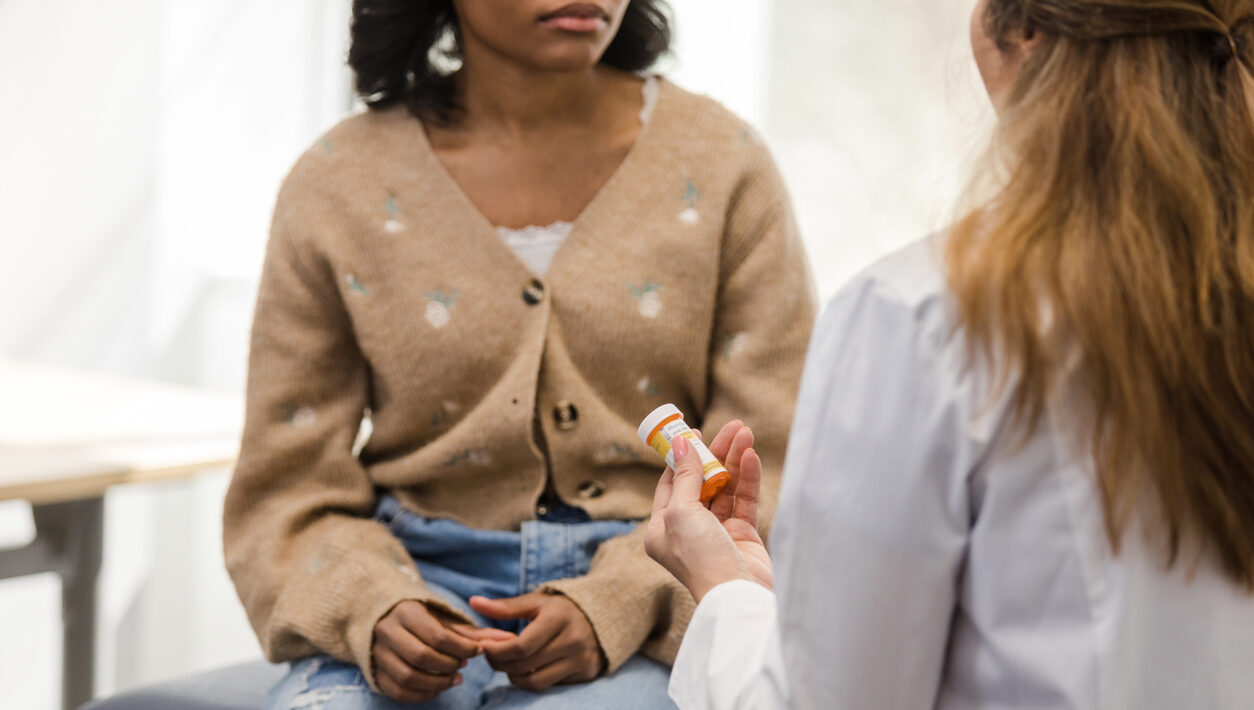 Young female college student discusses medicine with doctor