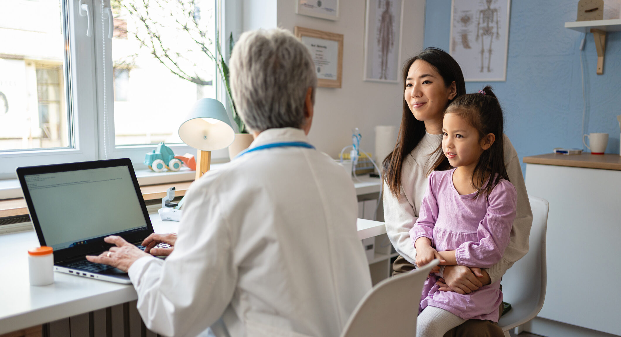 Woman Japanese ethnicity bring her multiracial daughter for an annual medical check-up with a senior Caucasian female pediatrician