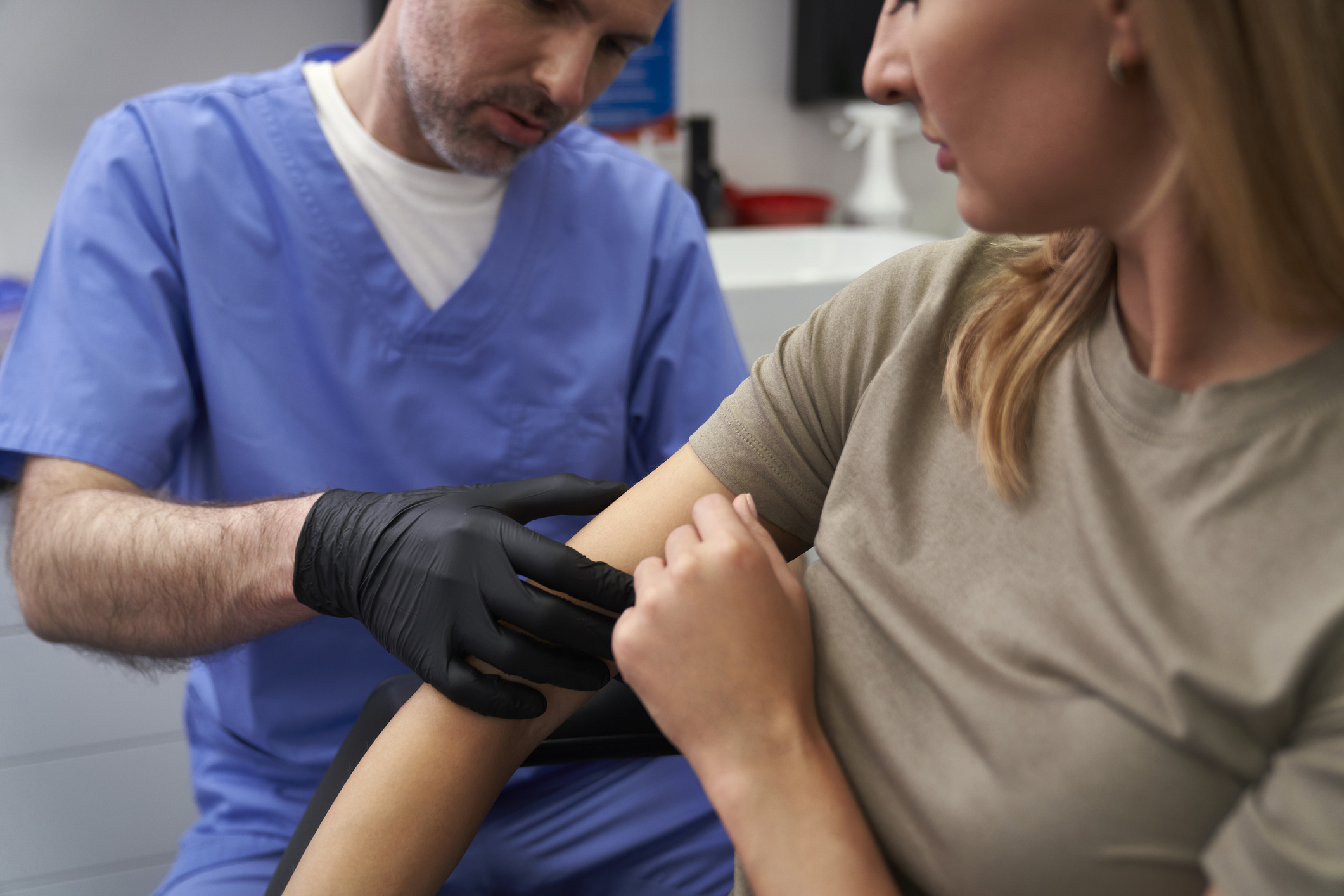 Doctor checking mark on woman's arm