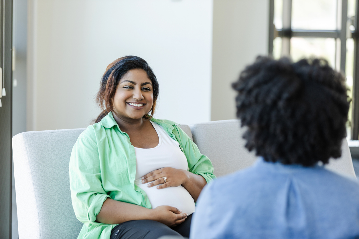 Cheerful young pregnant woman listening to doctor