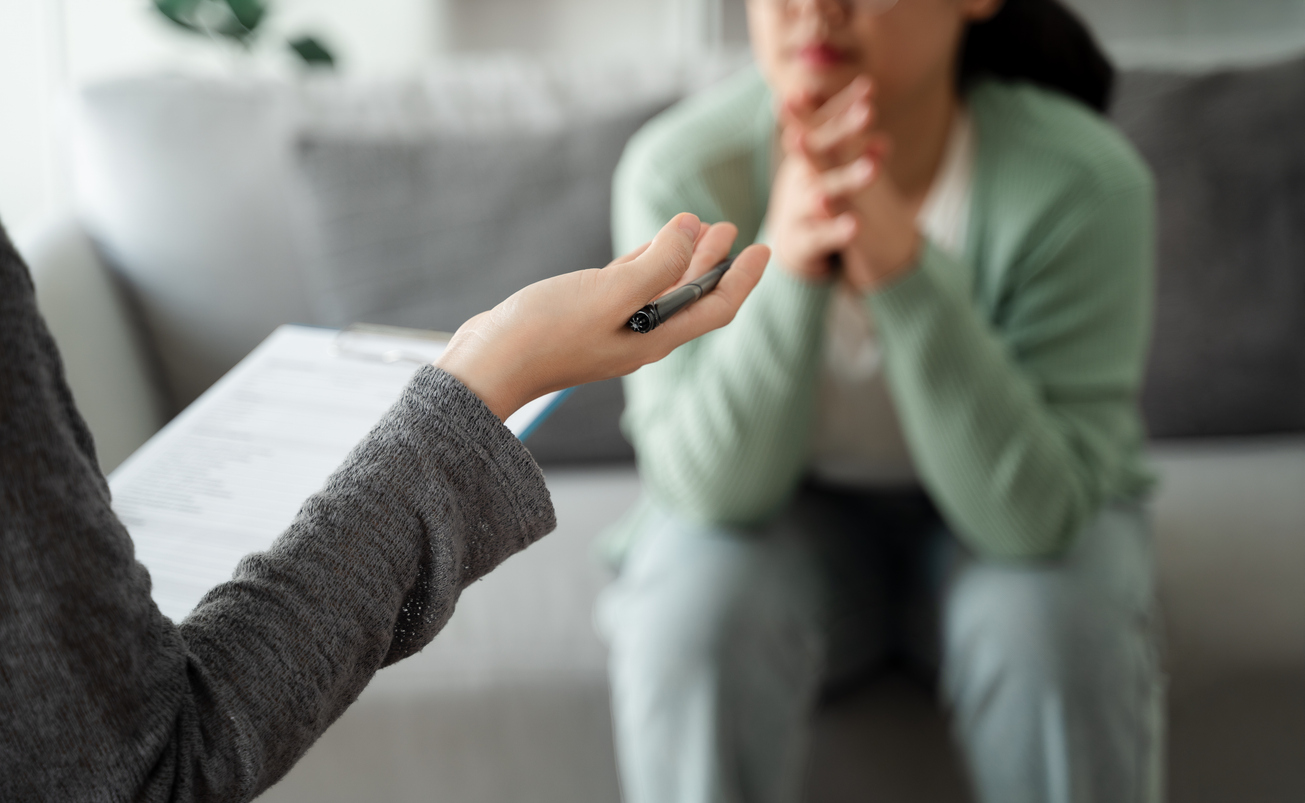 Therapist speaking with a woman during a mental health counseling session in a private office setting.