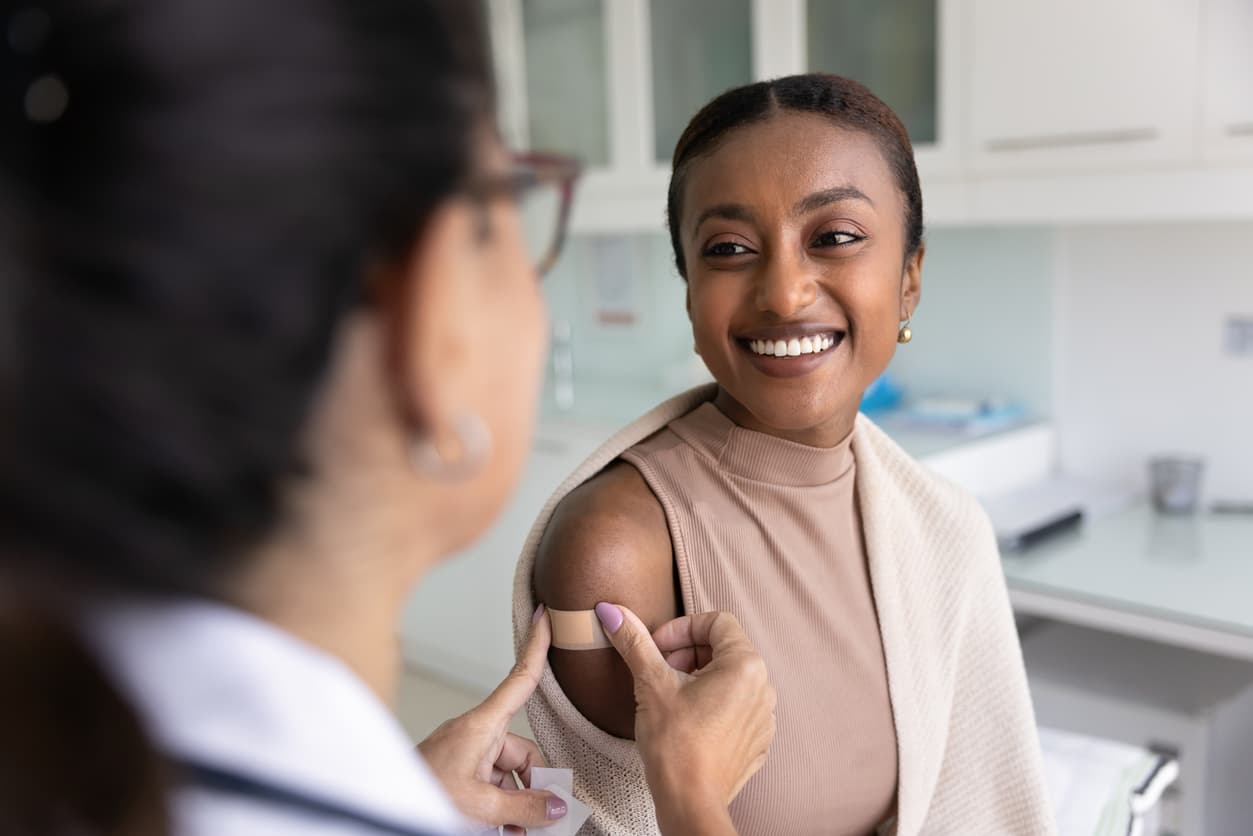 Woman smiling after receiving a vaccine from a healthcare provider during a routine medical appointment.