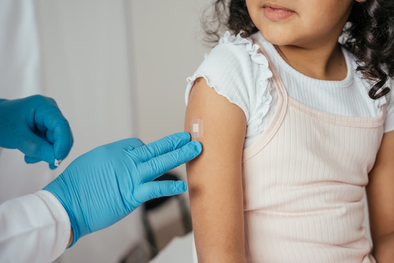 Young girl receiving a vaccine injection from a healthcare professional during a pediatric medical appointment.