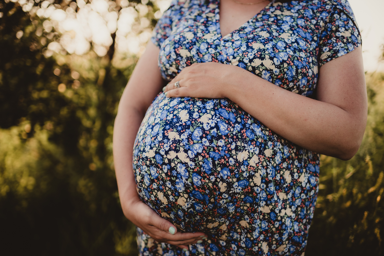 Pregnant woman overdue in blue flower dress outdoors in summer