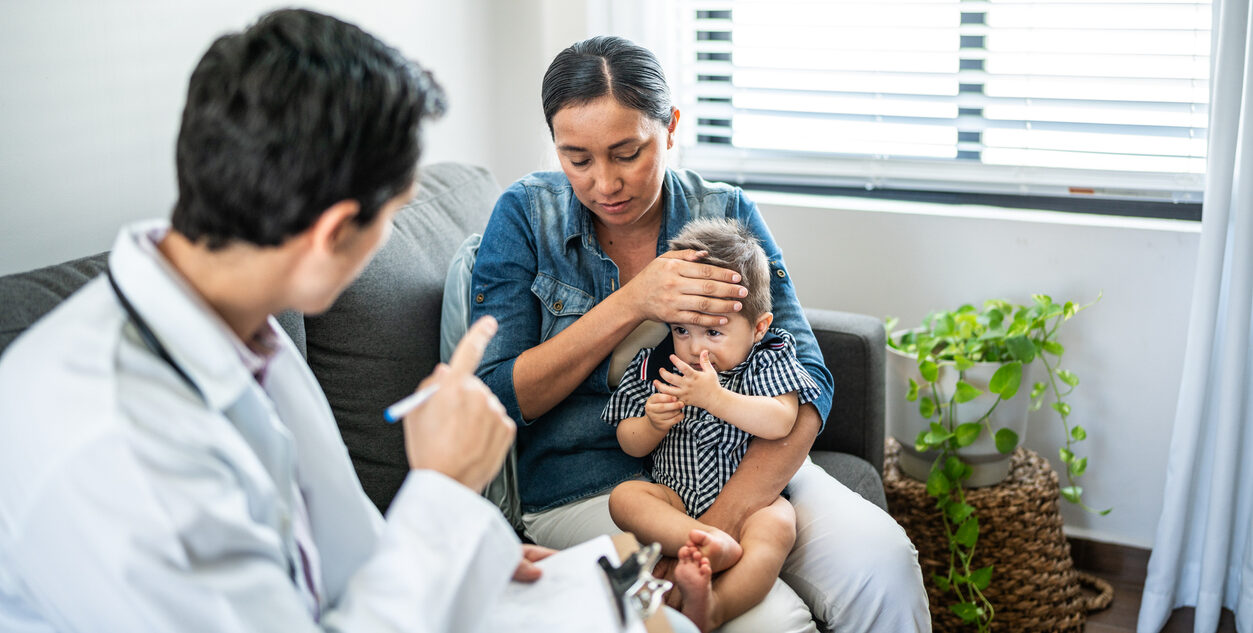Pediatrist examining baby boy with mother at home