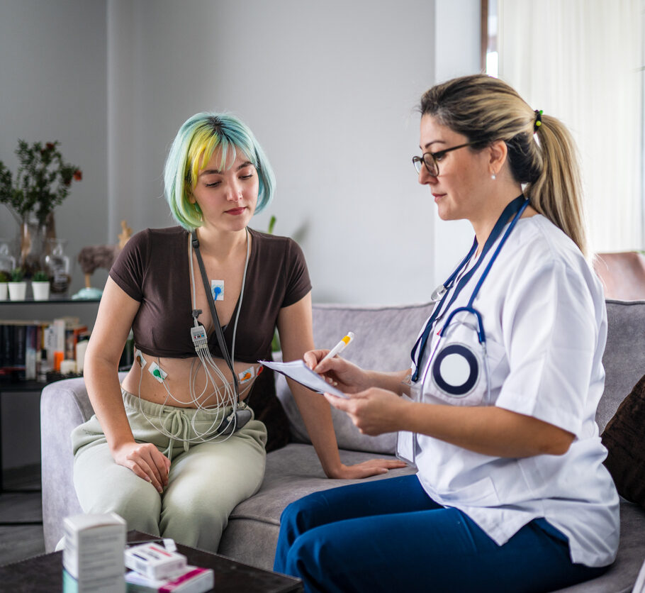 Young woman with heart condition is being tracked with Holter and caregiver visit her at home