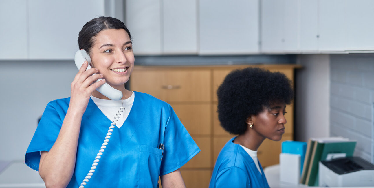 Healthcare professionals managing front desk duties within a medical facility reception area.