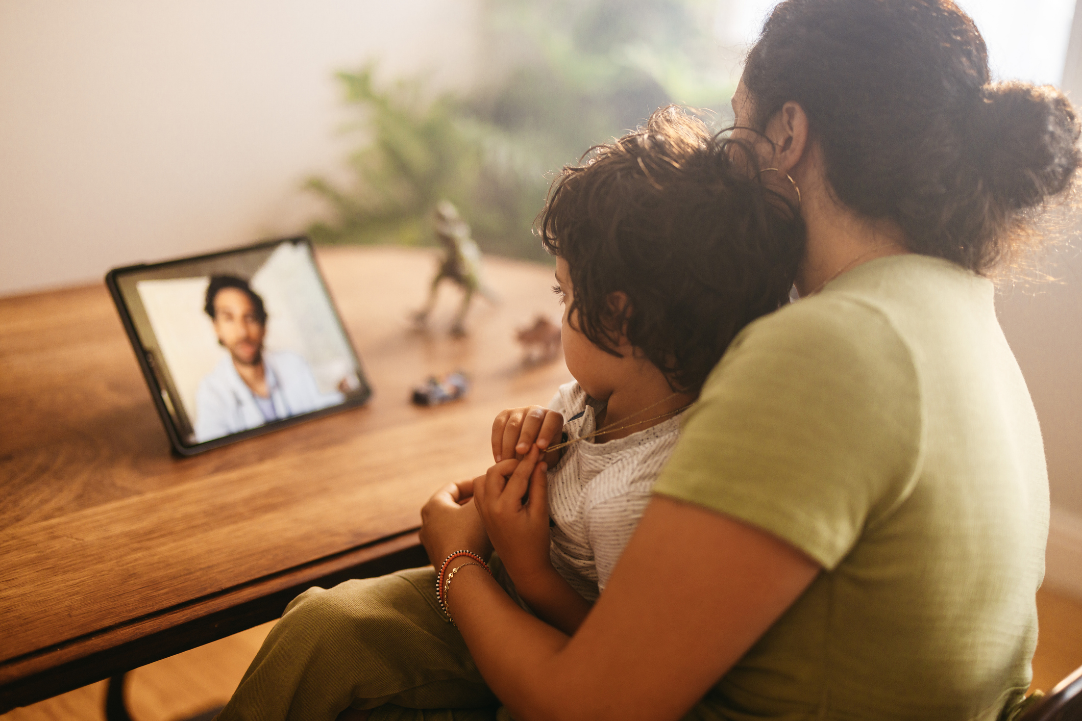 Mother and child video calling their family doctor on a digital tablet. Mother and son having an online consultation with their paediatrician. Loving young mother caring for her sick son at home.