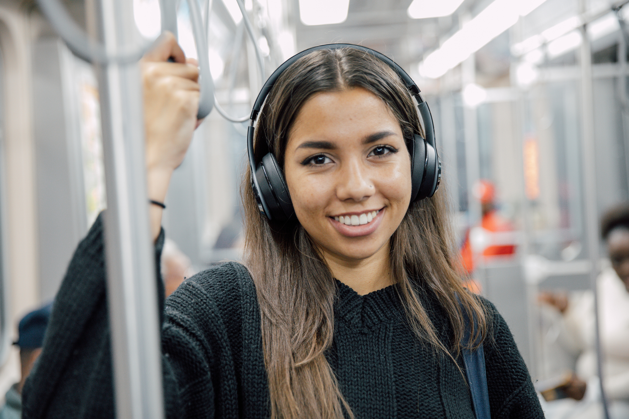 Young adult woman using public transportation in a city, standing and sitting inside a train. Daily commuting and urban mobility concept.